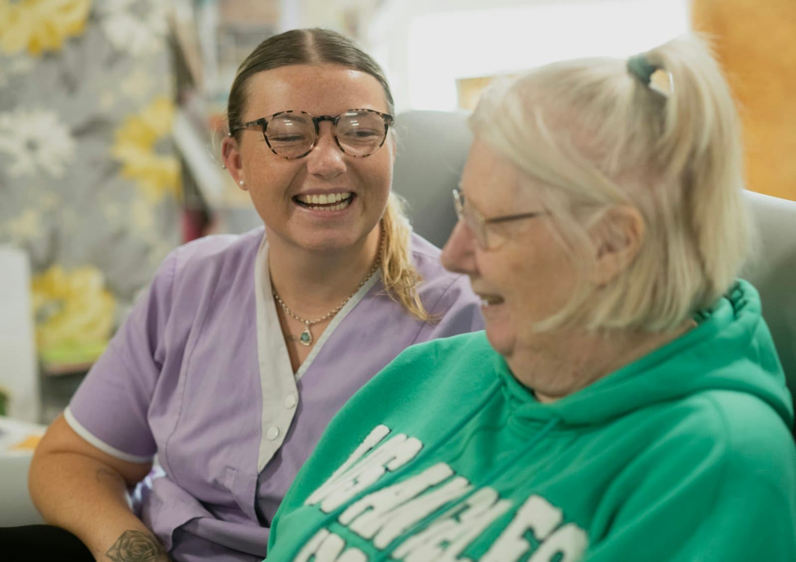 A caregiver and an elderly patient laughing together